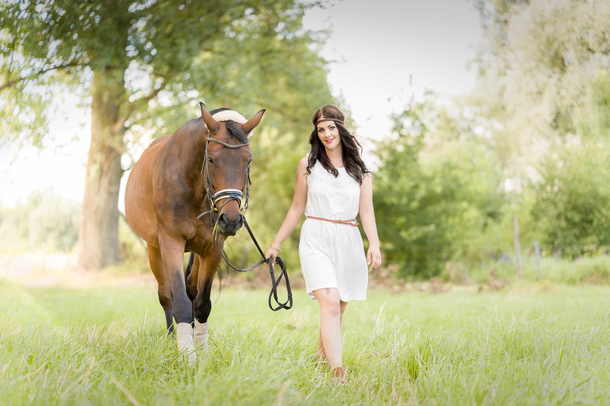 Model mit Pferd läuft über grüne Wiese, aufgenommen von www.emotive-photography.de